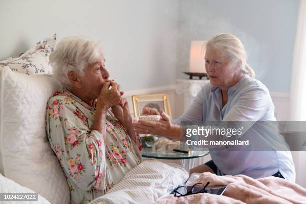 a woman teaches her mother how to smoke marijuana joint medicinal cannabis - end of life care stock pictures, royalty-free photos & images