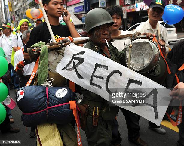 Protesters from Taiwan's main opposition Democratic Progressive Party dressed like an old Kuomintang soldier smokes as he marches during an anti-ECFA...