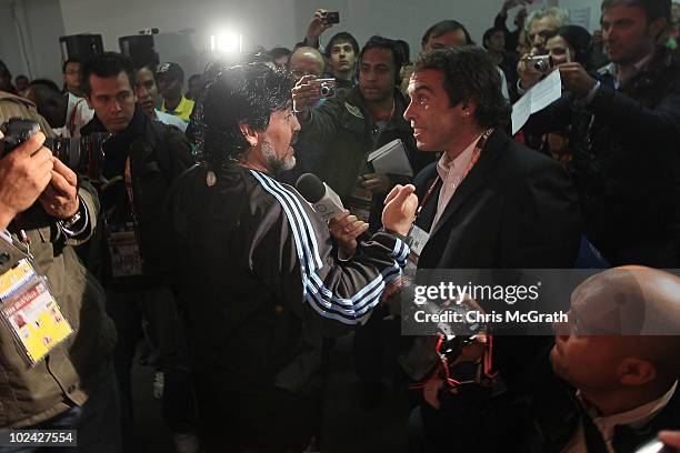 Argentina's head coach Diego Maradona stops to talk to a television reporter after climbing over a barricade and into waiting media during a press...