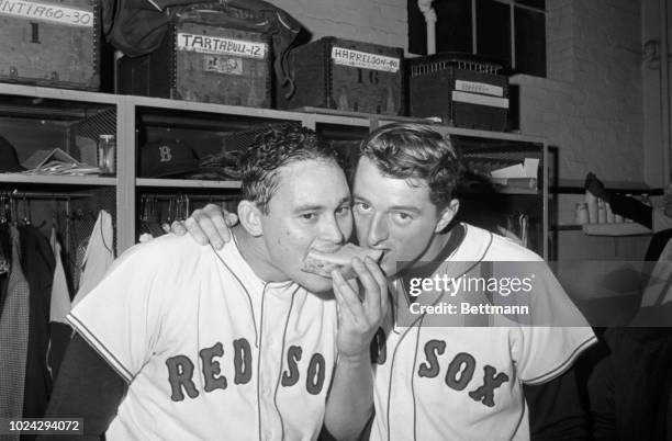 Red Sox' Jose Santiago and Ken Harrelson share a piece of watermelon in dressing room after the Sox defeated the Chicago White Sox 10-2, to remain in...