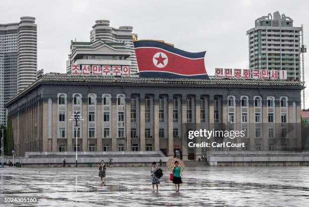 Women walk across Kim Il-sung Square as a huge North Korea flag is displayed atop the Central Committee of the Workers' Party of Korea building, on...