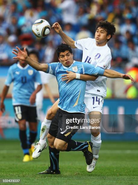 Luis Suarez of Uruguay is challenged by Lee Jung-Soo of South Korea during the 2010 FIFA World Cup South Africa Round of Sixteen match between...