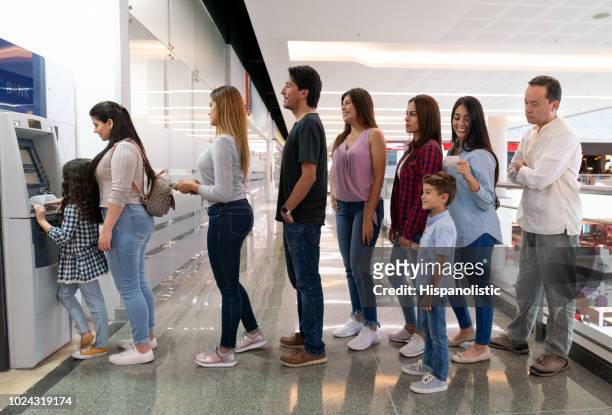 gente haciendo cola en el centro comercial para retirar dinero de un cajero automático - lining up fotografías e imágenes de stock