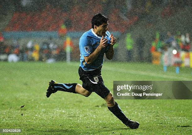 Luis Suarez of Uruguay celebrates scoring his second goal in the driving rain during the 2010 FIFA World Cup South Africa Round of Sixteen match...