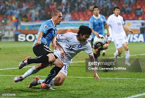 Diego Perez of Uruguay challenges Kim Dong-Jin of South Korea during the 2010 FIFA World Cup South Africa Round of Sixteen match between Uruguay and...