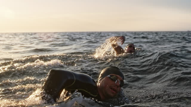 SLO MO TS Two open water swimmers swimming front crawl at sea in sunshine