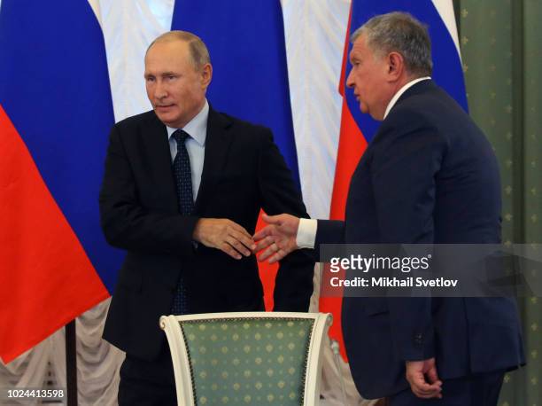 Russian President Vladimir Putin greets Rosneft's President Igor Sechin during a meeting with governors and governmental officials on August 27, 2018...