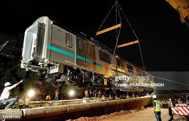 Crane uploads one of four coaches of Delhi Metro onto tracks in New Delhi on June 27, 2010. Delhi Metro Rail Corporation announced that the trial...