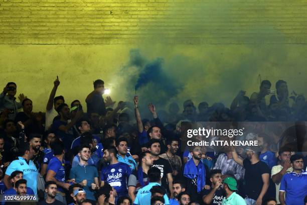 Iranian fans cheer for their team during the AFC Champions League football match Al-Sadd vs Esteghlal FC at the Azadi stadium in Tehran on August 27,...