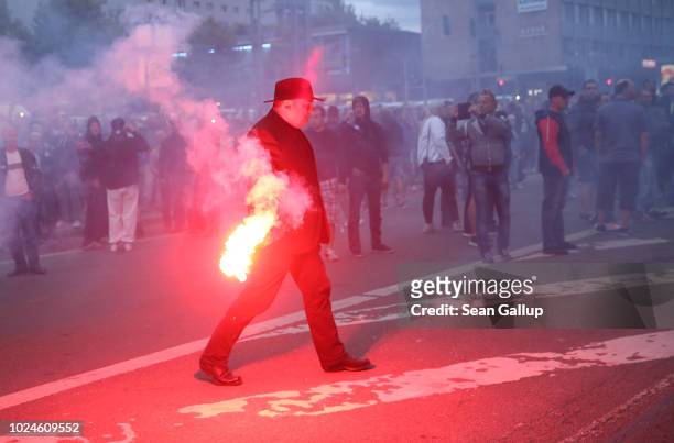 Jens Lorek, a lawyer for the right-wing Pegida movement, carries away flares thrown during a confrontation between left and right-wing protesters the...