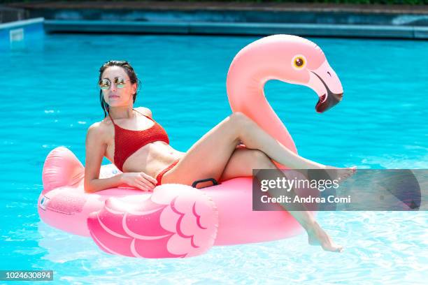 happy young woman with pink flamingo float in swimming pool - standing water stock pictures, royalty-free photos & images