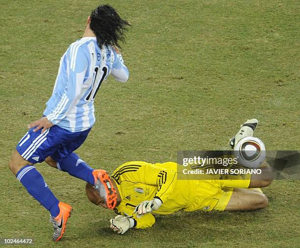 Argentina's striker Carlos Tevez jumps over Mexico's goalkeeper Oscar Perez who drops the ball before Prez scores the first goal during the 2010...