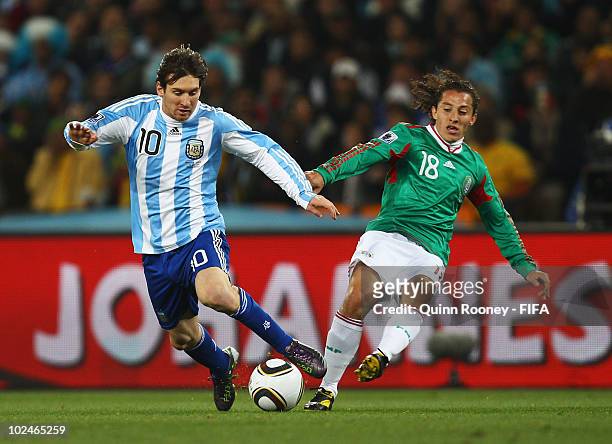 Lionel Messi of Argentina is challenged by Andres Guardado of Mexico during the 2010 FIFA World Cup South Africa Round of Sixteen match between...
