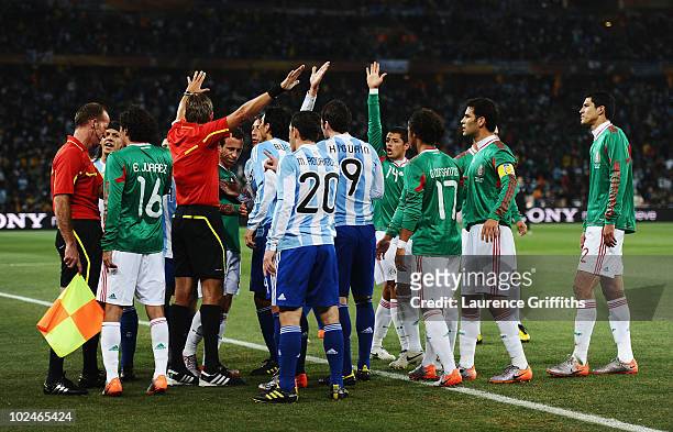 Referee Roberto Rosetti urges players away from referee assistant Stefano Ayroldi over the Carlos Tevez goal during the 2010 FIFA World Cup South...