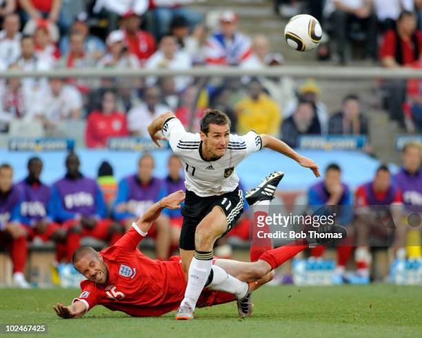 Miroslav Klose of Germany clashes wins the ball against Matthew Upson of England during the 2010 FIFA World Cup South Africa Round of Sixteen match...