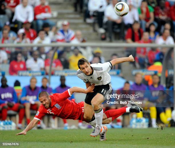 Miroslav Klose of Germany clashes wins the ball against Matthew Upson of England during the 2010 FIFA World Cup South Africa Round of Sixteen match...