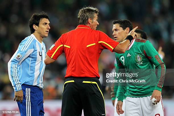 Referee Roberto Rosetti intervenes as Nicolas Burdisso of Argentina and Guillermo Franco of Mexico argue during the 2010 FIFA World Cup South Africa...