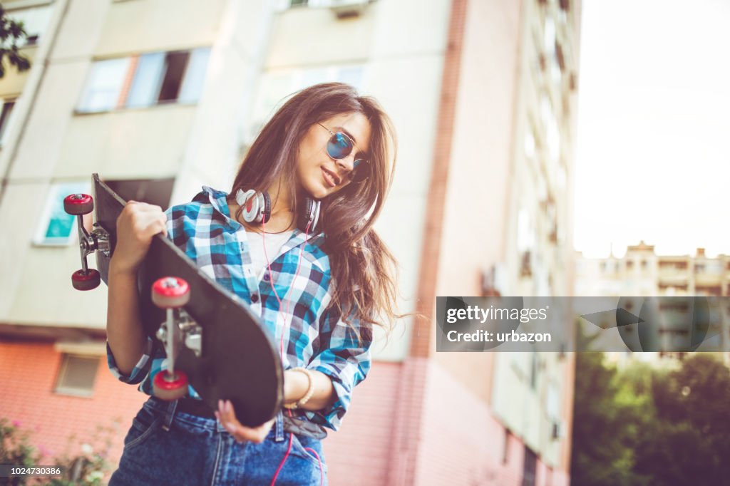 Girl in checkered shirt with skateboard