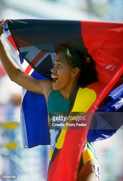 Cathy Freeman of Australia celebrates with both Australian and Aboriginal flags after winning the 400 metres final during the Commonwealth Games in...