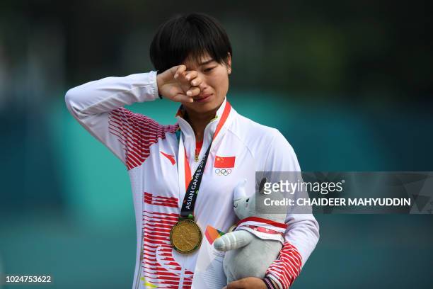 Gold medallist China's Zhang Xinyan reacts on the podium during the awards ceremony for the archery recurve women's individual event at the 2018...