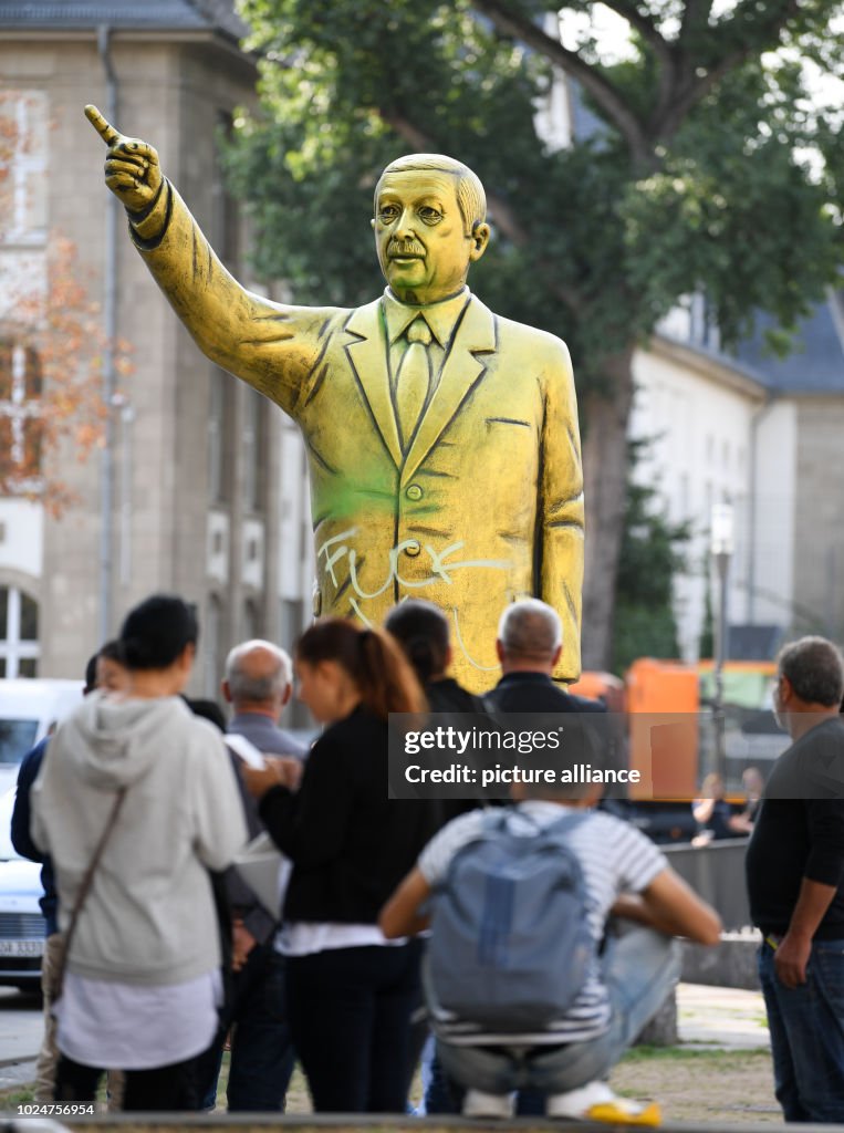 Passers-by stand in front of a golden Erdogan statue on the Square of ...