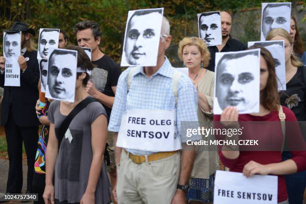 People wearing masks depicting Ukrainian film director Oleg Sentsov take part in a protest on August 28 in front of the Russian embassy in Prague....