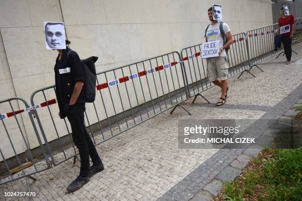 People wearing masks depicting Ukrainian film director Oleg Sentsov take part in a protest on August 28 in front of the Russian embassy in Prague. -...