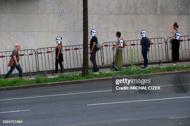 People wearing masks depicting Ukrainian film director Oleg Sentsov take part in a protest on August 28 in front of the Russian embassy in Prague. -...