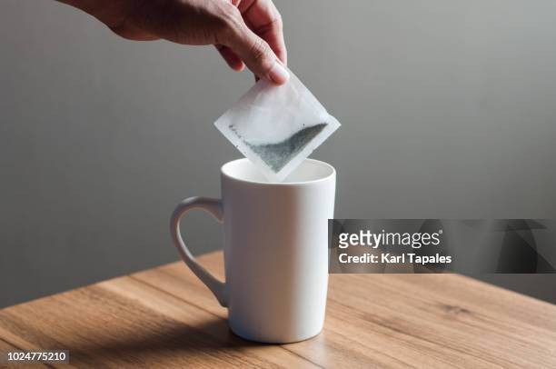 putting a tea bag into a white mug - chamomile tea 個照片及圖片檔