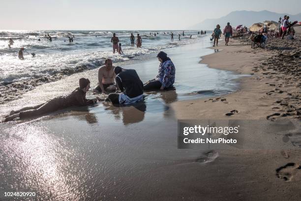 On 23 August women wearing burkinis sit on the sandy Patara Beach, a popular tourist destination on the Mediterranean coast in Antalya, Turkey, also...