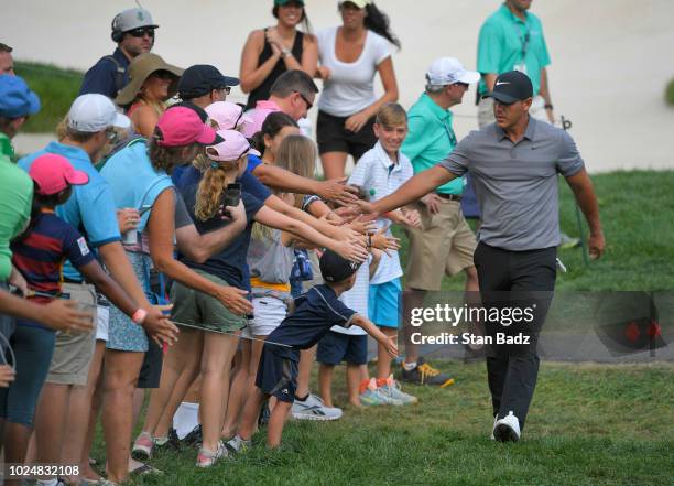 Brooks Koepka high fives fans as he walks to the 18th hole during the final round of THE NORTHERN TRUST at Ridgewood Country Club on August 26, 2018...