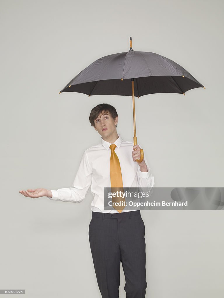 Businessman standing under an umbrella 