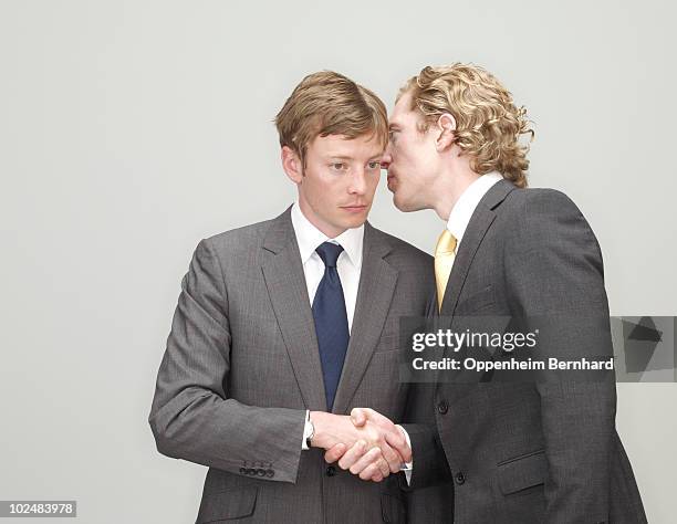 businessmen whispering and shaking hands - fluisteren stockfoto's en -beelden