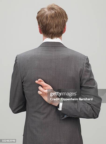 man in suit with fingers crossed behind back - mãos-atrás-das-costas imagens e fotografias de stock