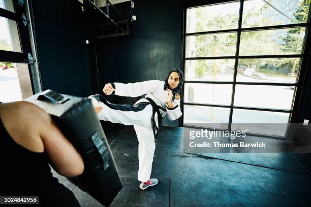 female muslim self defense instructor demonstrating kick during class in gym - martial arts stock pictures, royalty-free photos & images
