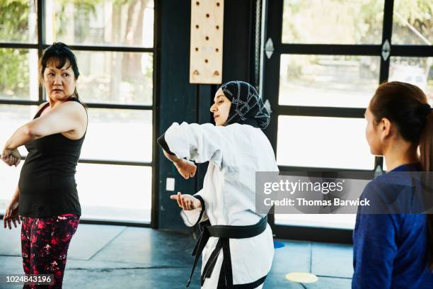 female muslim self defense instructor showing students technique during class in gym - defensa propia fotografías e imágenes de stock