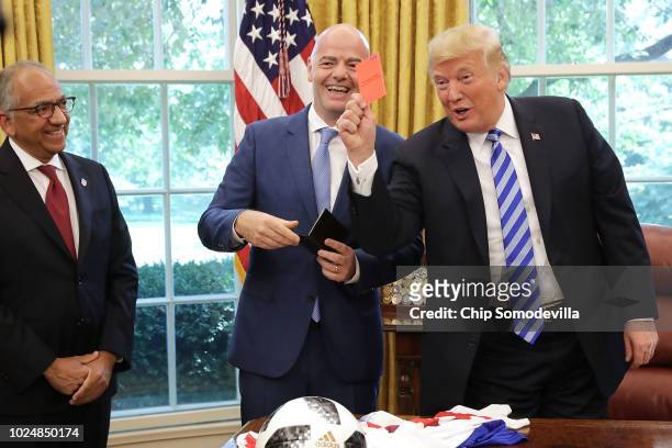 President Donald Trump pretends to give a red card to members of the news media while meeting with FIFA President Gianni Infantino and U.S. Soccer...