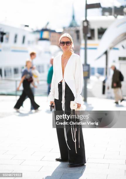 Celine Aagaard wearing black wide leg pants, white blouse with fringes, mini bag is seen during Stockholm Runway SS19 on August 28, 2018 in...