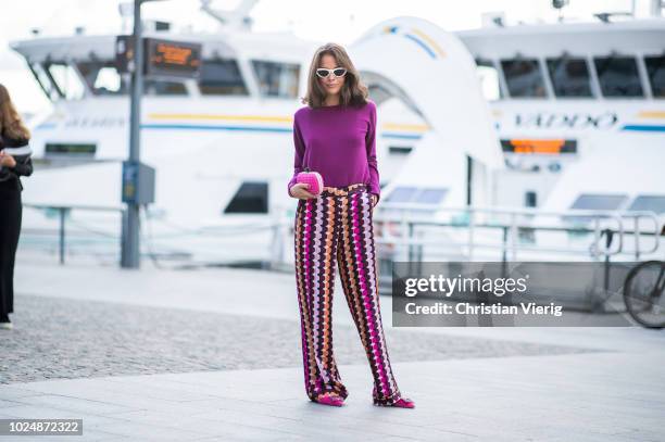 Guest wearing purple knit, multi colored wide leg pants, pink clutch seen during Stockholm Runway SS19 on August 28, 2018 in Stockholm, Sweden.