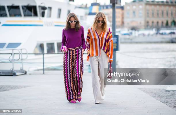 Guests wearing purple knit, multi colored wide leg pants, pink clutch and a guest wearing striped button shirt, wide leg pants, red Chanel bag seen...