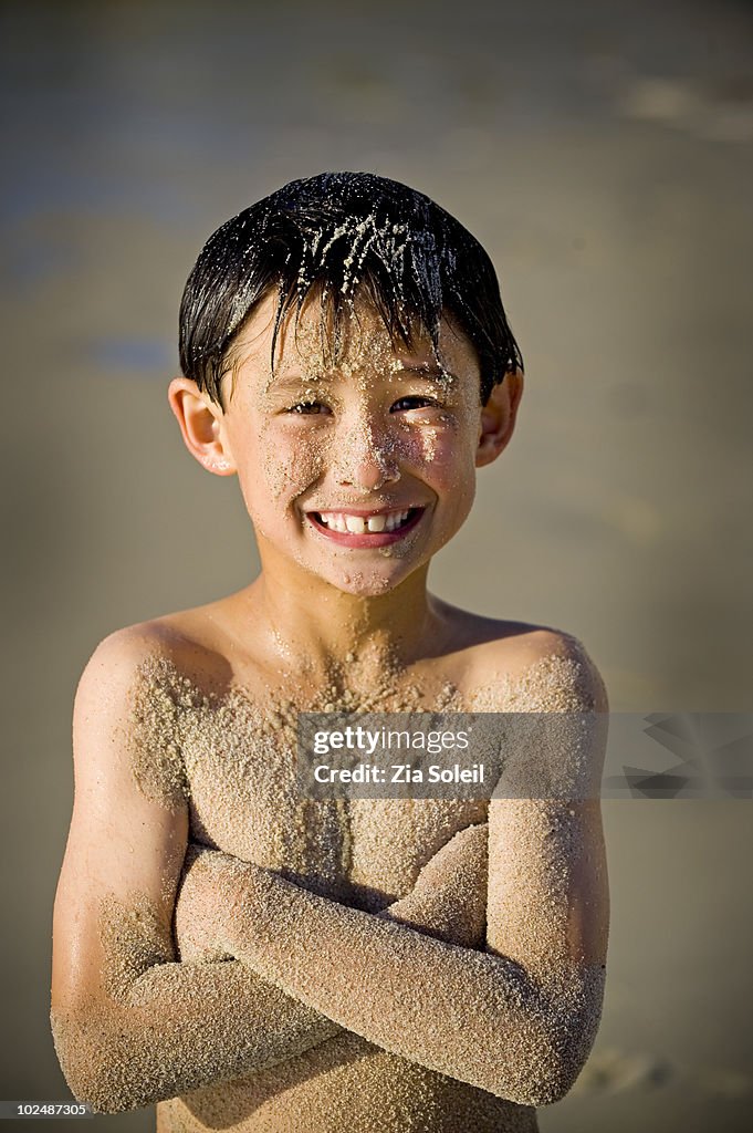 Smiling, very sandy boy at the beach