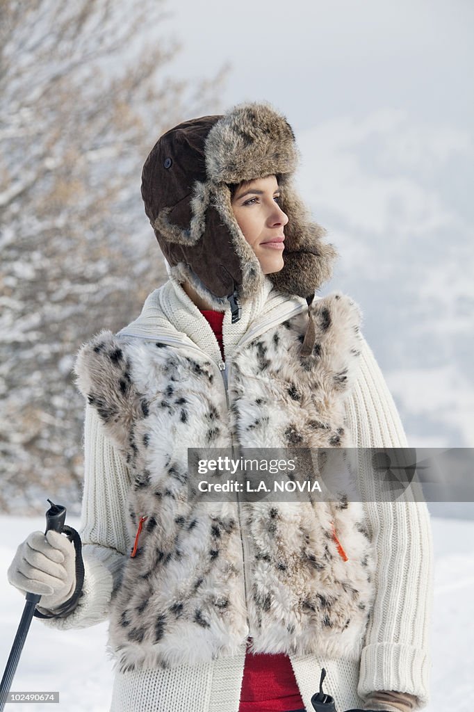 Young woman with ski poles, looking away