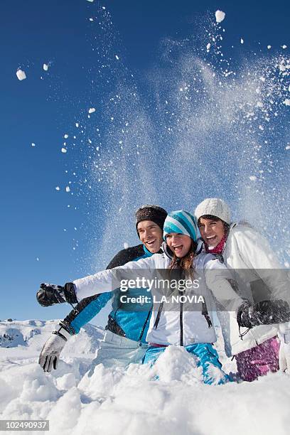 couple and daughter in ski wear, throwing snow in air - trois vallees stock pictures, royalty-free photos & images
