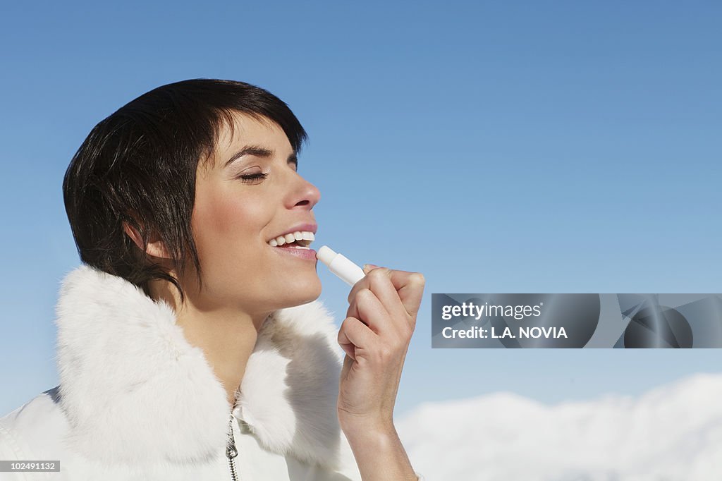 Young woman applying lip balm