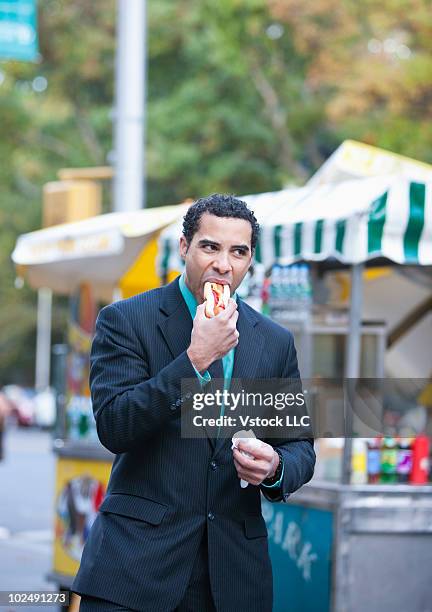 businessman eating a hotdog - hotdog stand nyc photos et images de collection