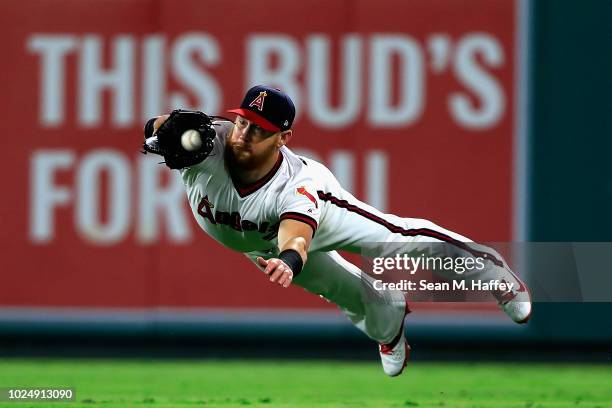 Kole Calhoun of the Los Angeles Angels of Anaheim dives to catch a line drive hit by Nolan Arenado of the Colorado Rockies during the fourth inning...