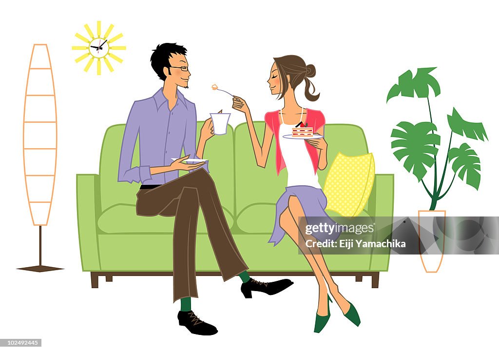 Young couple in living room sharing cake and coffee