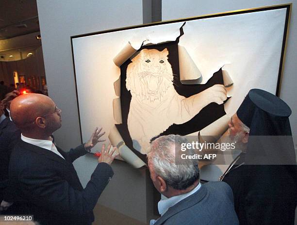 Saif al-Islam Kadhafi, the son of Libyan leader Moamer Kadhafi, gestures looks at a piece of art during the opening of an exhibition entitled 'The...