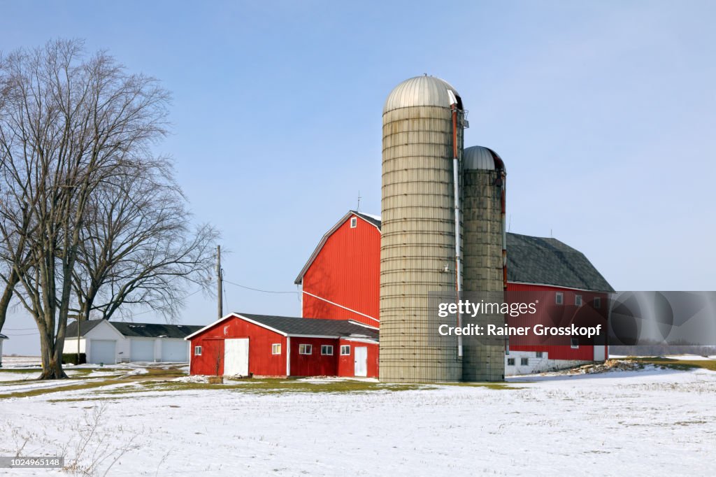 Red barn and farm in a snow-covered winter landscape