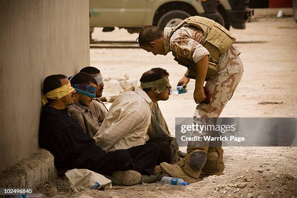 An Iraqi soldier from 2nd Division gives water to detainees after returning to their base from a morning mission on June 5 , 2010 in Mosul, Iraq....